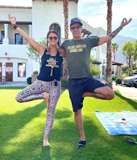 a man and woman doing yoga in front of a house