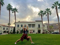 a woman doing yoga in front of a house with palm trees