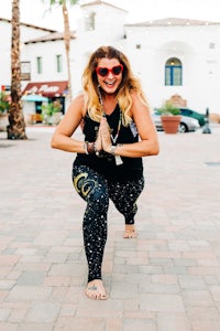 a woman in a black tank top and leggings posing for a photo