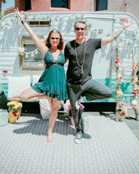 a man and woman posing in front of a camper trailer