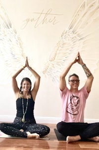 two people doing yoga in front of a wall with wings